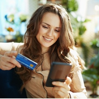Happy young woman using credit card