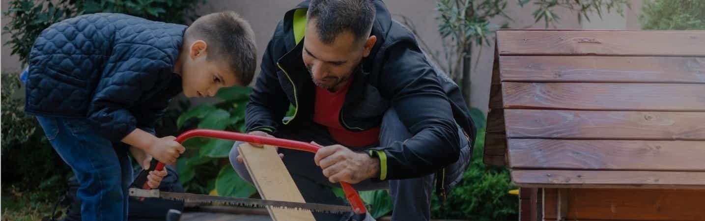 Father and son sawing wood for home improvement