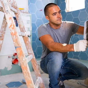 Man working on tile in bathroom